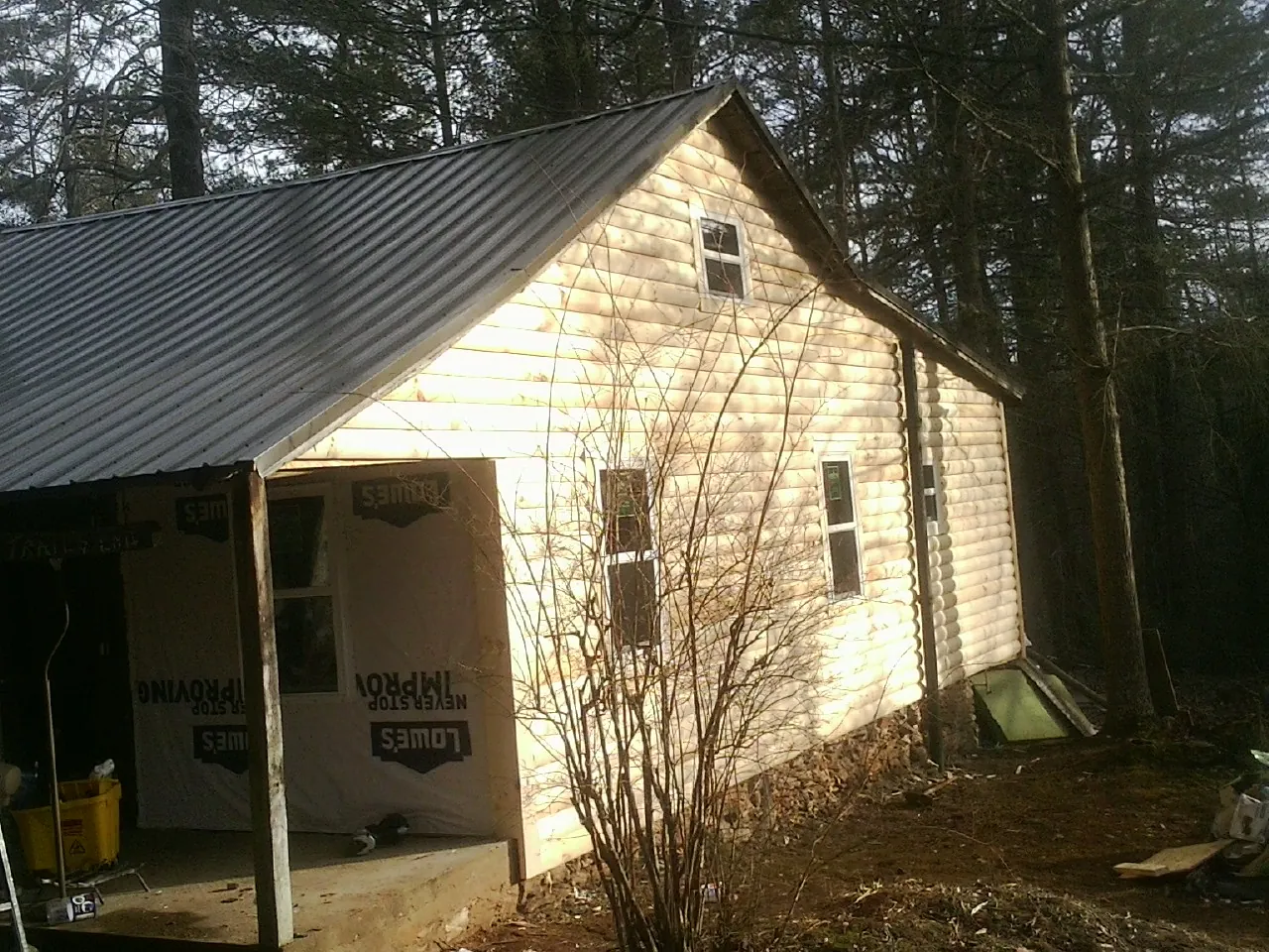 Log siding gable end under a dark metal roof edge in Malvern