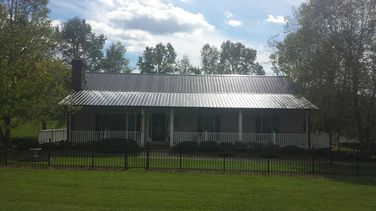 Gray metal roof on a brick ranch with a full width front porch — Gutter Guard Installation work by our crew in Malvern