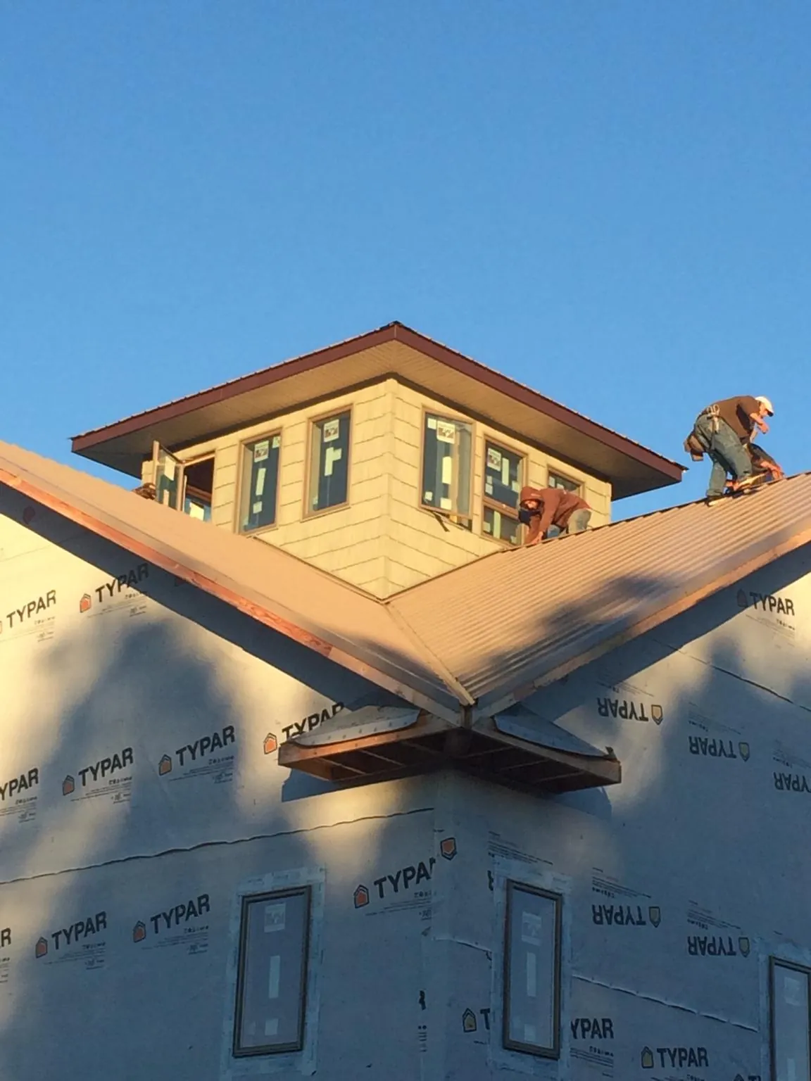 Roofers working around a rooftop cupola on a new metal roof at sunset — Roof Waterproofing in Malvern by Roofing Brothers